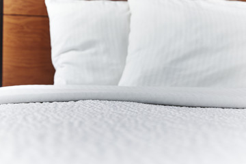 Fototapeta na wymiar Folded White Bed Covers with pillows on a made bed with shallow depth of field