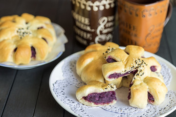 Bread stuffed with sweet pumpkin on white dish on wooden table with couple coffee cup background.