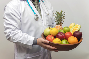 Healthy and nutrition concept. Doctor holding bowl of fresh fruits and vegetables.