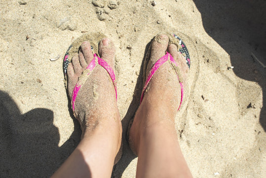 Woman feet with flip flops on the sand