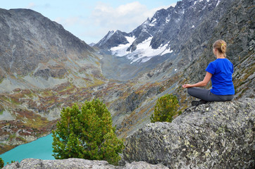 Naklejka na ściany i meble Молодая девушка сидит на скале над озером Куйгук на Алтае