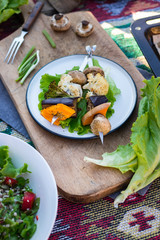 Baked grilled vegetables kebabbed on skewer sticks. Pumpkin, mushrooms, cauliflower, eggplant, roasted broccoli with salad fresh green leaves on plate. Vegan lunch, vegetarian dinner, paleo diet
