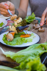 Baked grilled vegetables kebabbed on skewer sticks. Pumpkin, mushrooms, cauliflower, eggplant, roasted broccoli with salad fresh green leaves on plate. Vegan lunch, vegetarian dinner, paleo diet