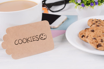 Paper card with "cookies" text and coffee with phone, cookies and glasses