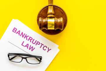 Words bankruptcy law written on the documents near judge gavel on yellow background top view copy space