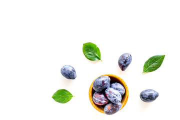 Blue plum for dessert. Purple plum and leaves pattern on white background top view copy space