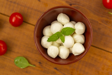 Italian food ingredients – mozzarella, tomatoes, arugula on rustic wooden table.