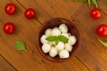 Italian food ingredients – mozzarella, tomatoes, arugula on rustic wooden table.