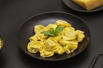 Traditional italian ravioli filled with ricotta cheese and spinach decorated with green leaves basil and grated parmesan