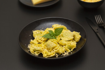 Traditional italian ravioli filled with ricotta cheese and spinach decorated with green leaves basil and grated parmesan