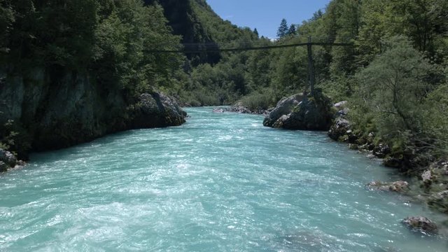 Aerial - Flying underneath the wooden bridge over beautiful emerald river