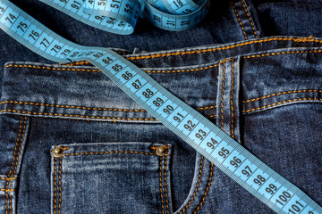 Blue jeans and a blue measuring tape close-up. Measurement of size. Diet and healthy.