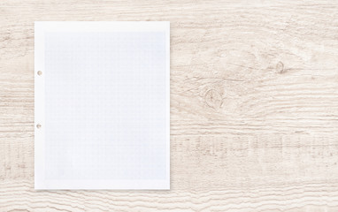 White paper sheet with grid line pattern on wood.