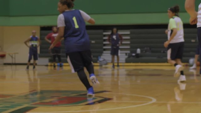 A female basketball player jukes around another player at practice.
