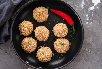 Raw meatballs in a pan on black background. Copy space.