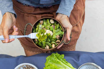 Woman hands hold a copper pot with cooked green beans, broccoli and mushrooms vegetables. Vegan vegetarian healthy food. Lunch or dinner.