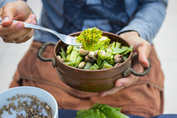 Woman hands hold a copper pot with cooked green beans, broccoli and mushrooms vegetables. Vegan vegetarian healthy food. Lunch or dinner.