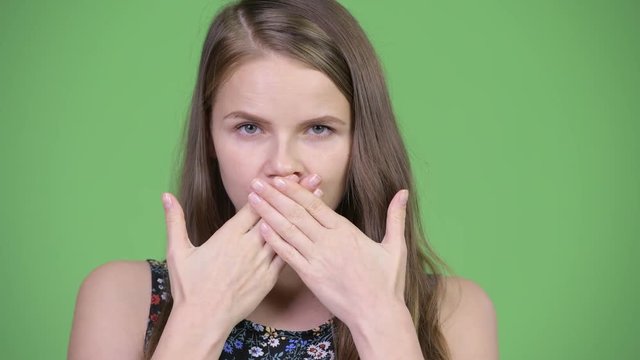 Head shot of young beautiful woman covering mouth as three wise monkeys concept