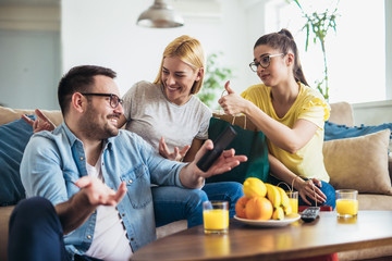 Young women sitting at home with bags after shopping. Young man watching tv.