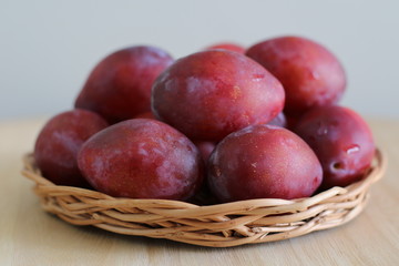 Ripe plums on straw plate