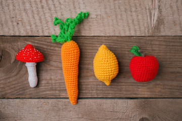 set of knitted toys lemon, carrot, apple, amanita on wooden background. Earlier tactile development...