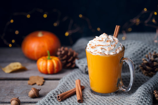 Pumpkin latte with spices. Boozy cocktail with whipped cream on top on a wooden background. Copy space.