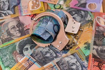 Steel handcuffs on australian dollars background close up