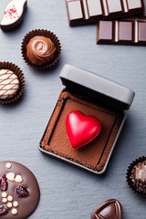 Heart shaped chocolate candy in a gift box on slate background. Top view.
