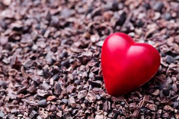 Heart shaped chocolate candy on crushed cocoa nibs. Close up. Copy space.