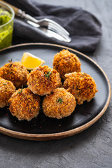 Homemade meatballs with thyme and green sauce on a black plate. Copy space.