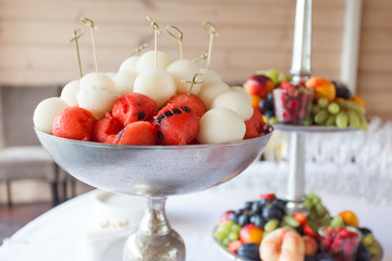Metal vase with watermelon and melon balls on skewers. Healthy food on event