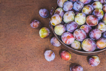 Fresh and ripe plums in metal bowl on rusty metal background with copy space. Closeup, selective focus