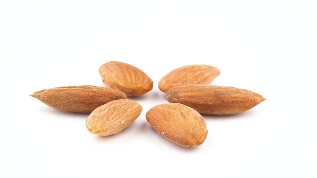 Six peeled almond nuts. Quickly rotating on the turntable. Isolated on the white background. Close up. Macro.
