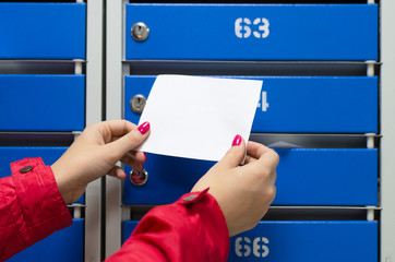 Blank letter paper page in female hand on a blue mailboxes background.
