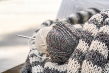 Hairs of wool, knitting needles and woolen clothes are prepared for work. Close-up