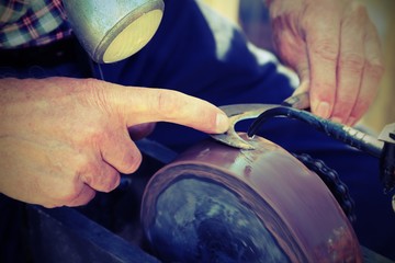 old man grinds while sharpening his billhook blade with vintage