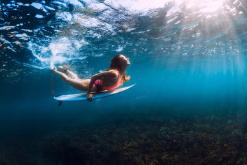 Attractive surfer girl dive underwater with wave.