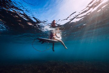 Surf woman sit at surfboard, Underwater view of surfer in ocean