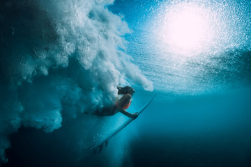 Surfer girl with surfboard dive underwater with under big ocean wave. - obrazy, fototapety, plakaty