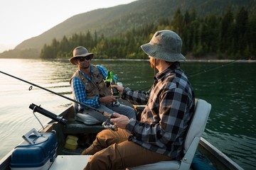 Two fishermen having beer while fishing in the river