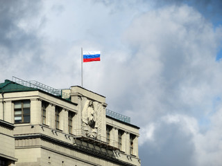 Russian flag on Parliament building in Moscow against cloudy sky. The State Duma facade with old...