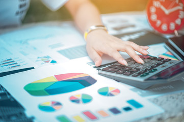 Fototapeta premium Woman sitting at desk and working at hand of book and financial documents close up