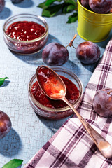 Close up of plum jam with ripe plums on background