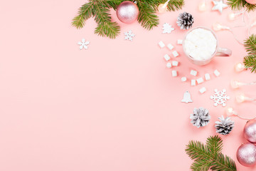 Christmas background with fir branches, lights, red giftboxes, pink decorations, hot drink with marshmallows on pink