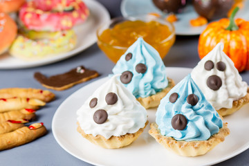 Halloween sweet treats, party food concept. White and blue cupcakes with faces close up.