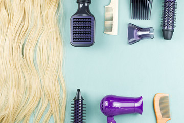 Hairdressing tools and hair extensions on blue wooden background. Top view