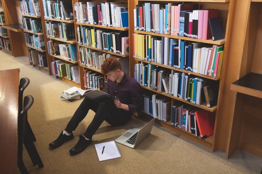 College Student Reading A Book In Library