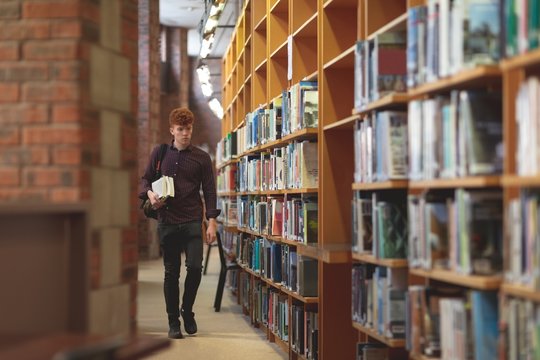 College student with books walking in library
