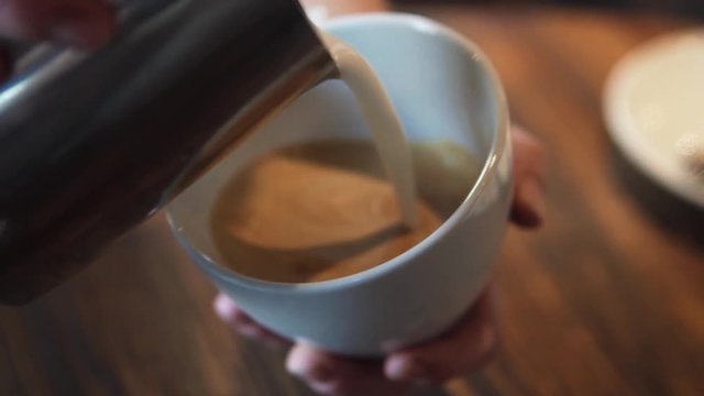 waiter pours a latte or cappuccino into a glass