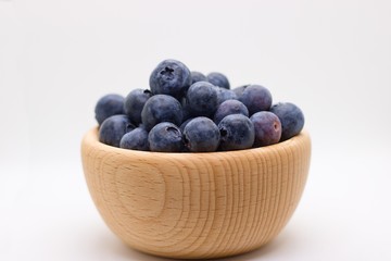 Side view of wooden bowl full of blueberries isolated on white background